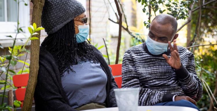 A man and a woman having a conversation in COVID-19 face masks outside
