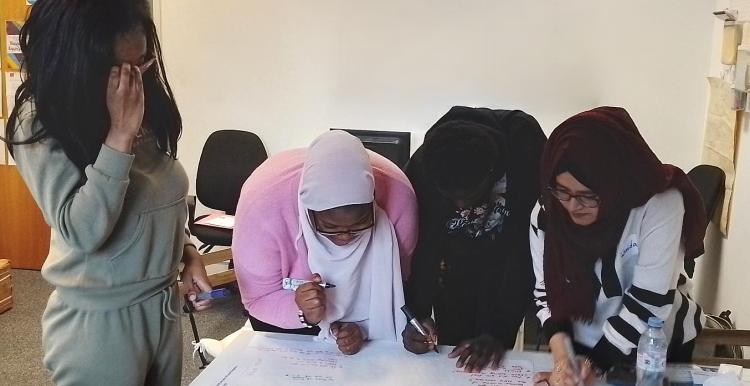 Four young person's researchers working in Healthwatch Greenwich office at a table on HPV research.