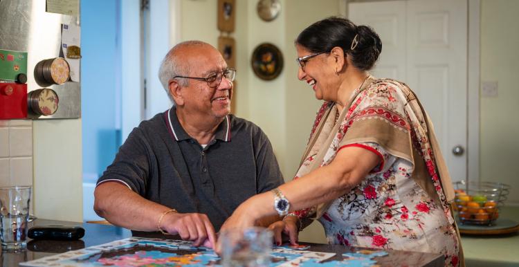 Man and woman at a table completing a puzzle.