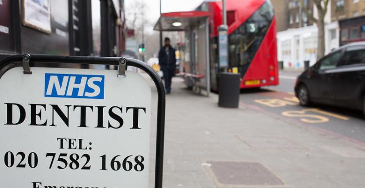Sign for NHS Dentist on sidewalk.