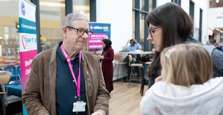 Healthwatch representative speaking to a mother with child.