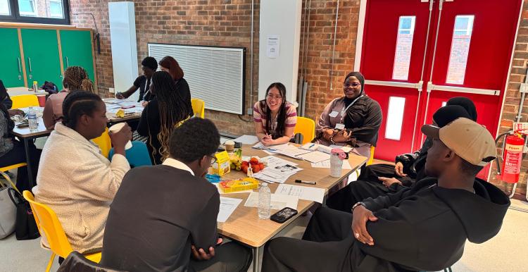 Young people seated around table speaking to Healthwatch Greenwich staff member.