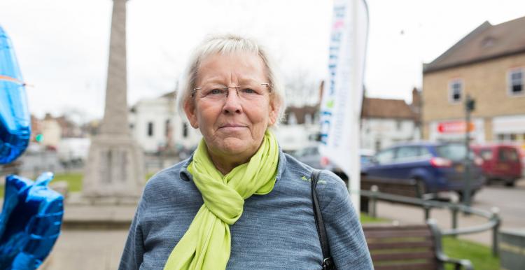 Older woman from the public wearing a green camera looking front on to the camera