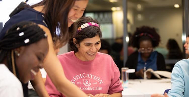 three women smiling and working together at a table