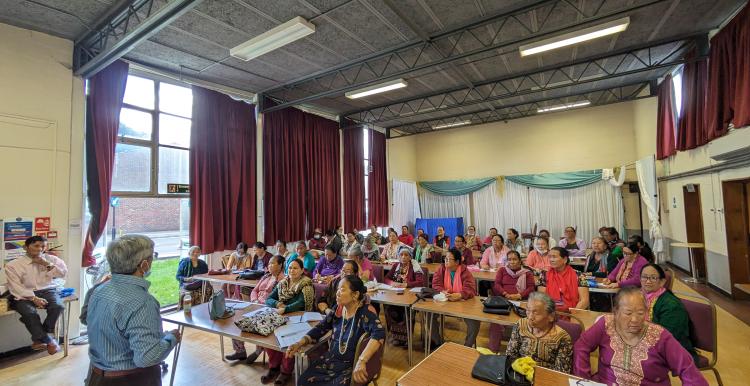 A group of Nepalese elderly women sitting in large hall.