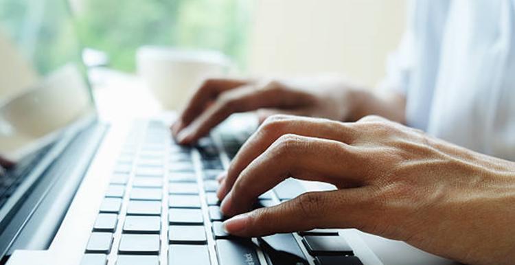 close up photo of hands typing on a laptop keyboard
