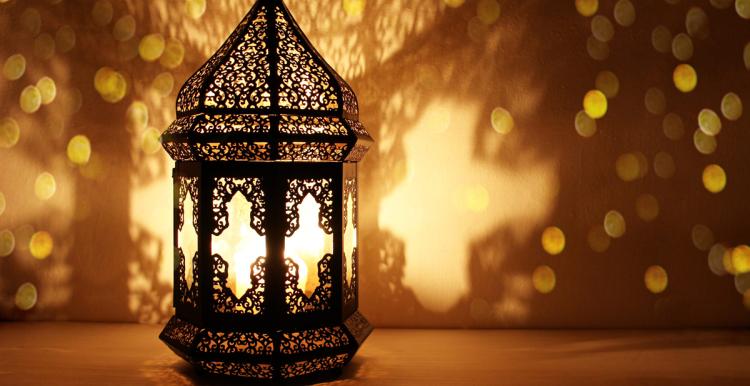 a lit lantern made of detailed metalwork throwing shadows onto the background