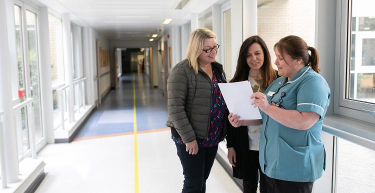 Three women talking in hospital corridor