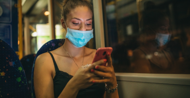 woman wearing mask on bus and looking at her phone