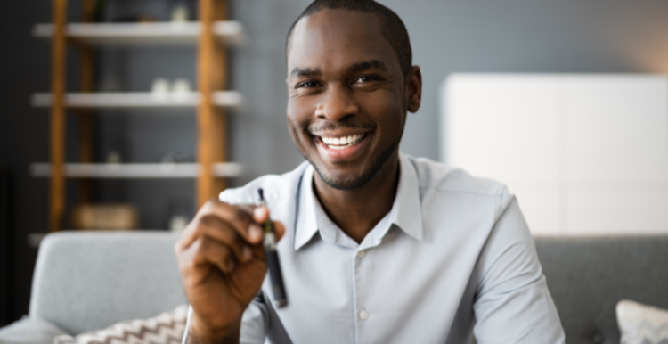 Man looks into camera holding e-cigarette and smiling