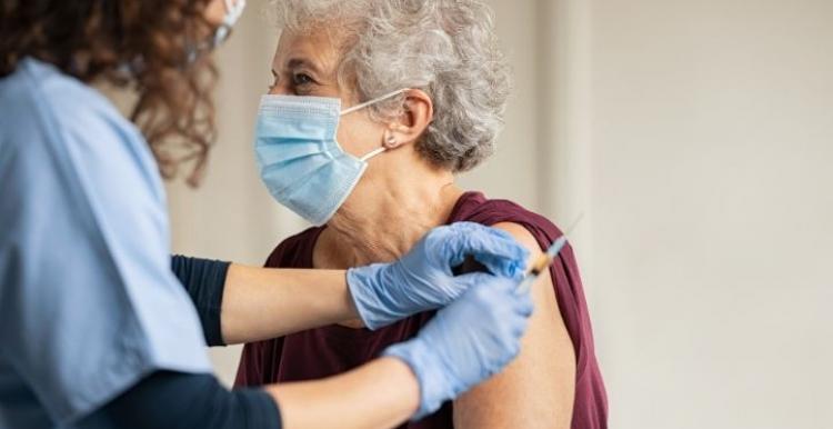 Older female person getting the COVID-19 vaccination from female health worker