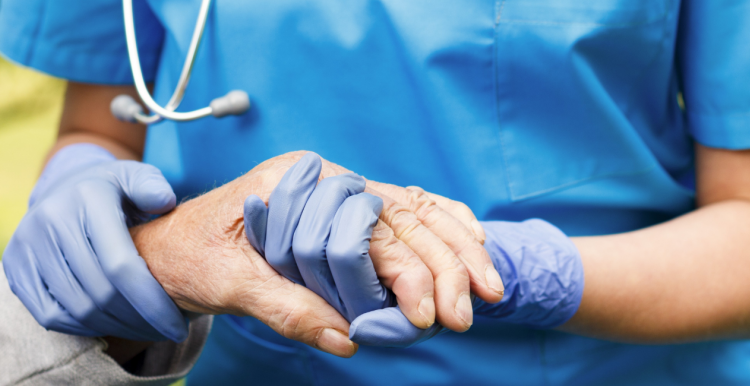 Nurse holding the hand of elderly person