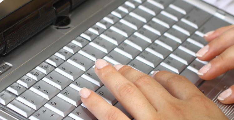 Close up of hands typing on a laptop keyboard Close up of hands typing on a laptop keyboard