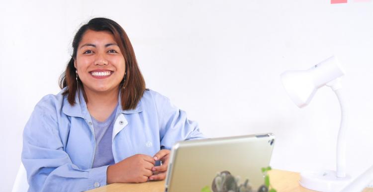 Lady in the blue jacket smiling in front of a laptop