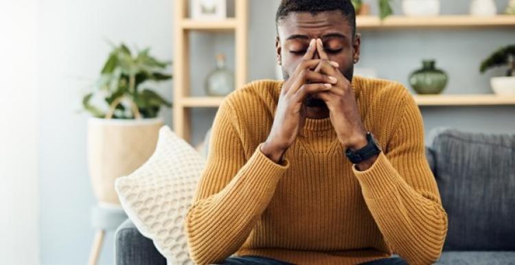 a young black man leaning his face on his hands