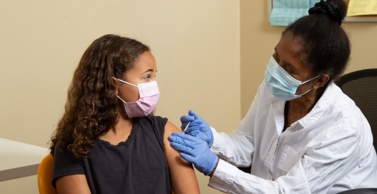 A female health worker vaccinating a young girl