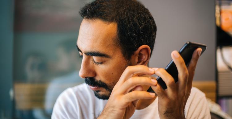 blind man uses phone to read something aloud