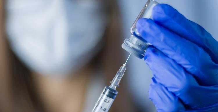 Doctor holds syringe and bottle with vaccine