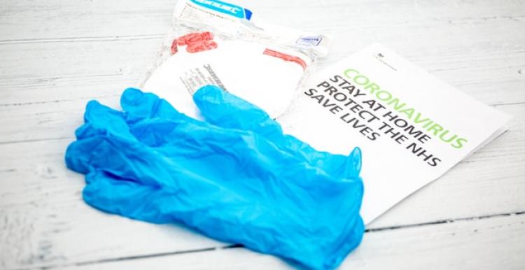 A government leaflet with coronavirus advice and a pair of blue disposable gloves