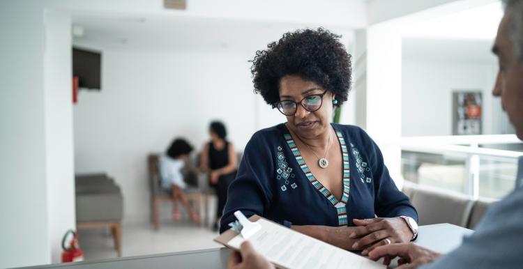 a black women reading a paper while standing at a counter