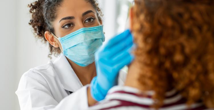 Medical professional wearing a COVID masks treats patient