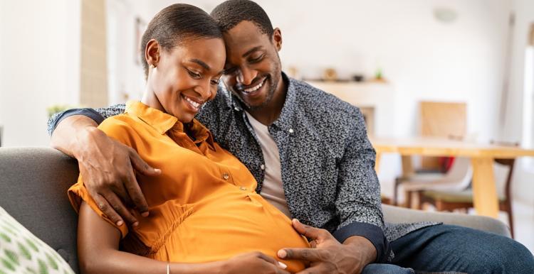 Pregnant woman sitting on a sofa with her partner