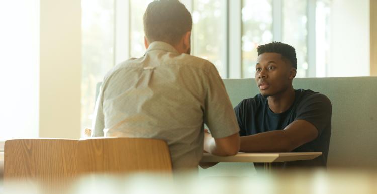 Young man talks to health professional in a bright room