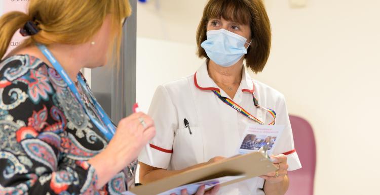 Two nurses wearing COVID face masks talk to each other