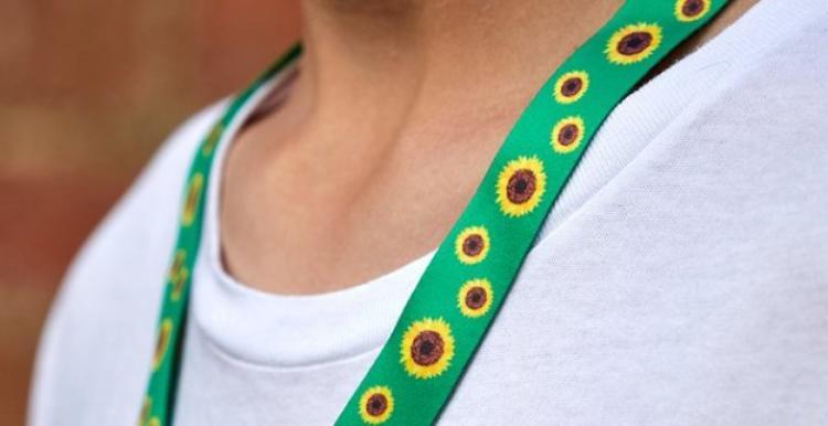 A person wearing the bright green and yellow Hidden Disabilities Sunflower lanyard