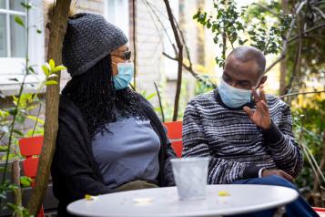 A man and a woman having a conversation in COVID-19 face masks outside