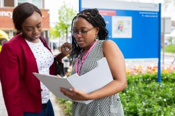 Two women looking down at folder outside a hospital