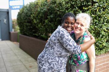 Two women embrace outside