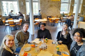 A group of you people sitting around a table in a cafe