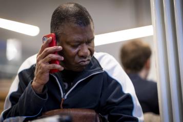 Man sitting at a table and holding a cell phone to his ear.