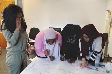 Four young person's researchers working in Healthwatch Greenwich office at a table on HPV research.