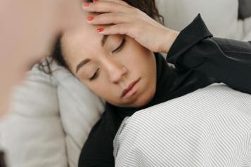 Young woman lying in bed while a paramedic takes her blood pressure.