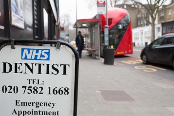 Sign for NHS Dentist on sidewalk.