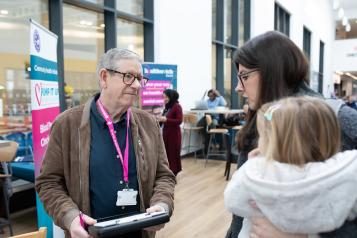 Healthwatch representative speaking to a mother with child.