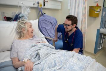 Older resident in hospital bed speaking with doctor