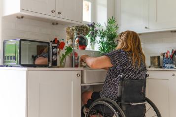 Woman using accessible sink in kitchen
