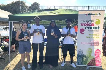 Healthwatch Greenwich young person's researchers standing in front of a stall holding leaflets about the HPV vaccine.