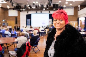 woman with short pink hair looks into camera