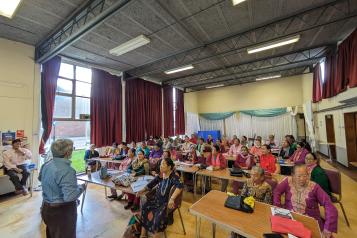 A group of Nepalese elderly women sitting in large hall.