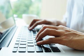 close up photo of hands typing on a laptop keyboard