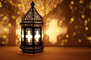 a lit lantern made of detailed metalwork throwing shadows onto the background