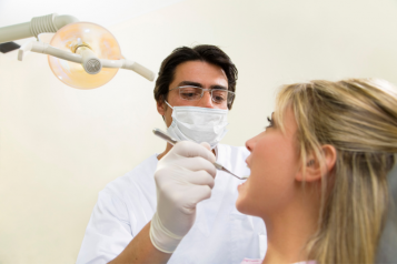 Dentist wearing protective face covering with patient