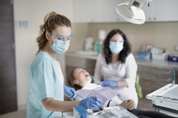 Dentists wearing protective face covering with patient