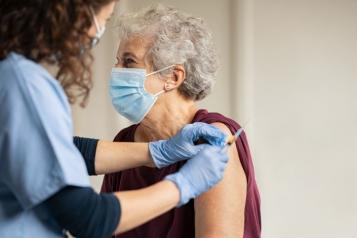 Older female person getting the COVID-19 vaccination from female health worker