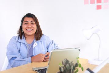 Lady in the blue jacket smiling in front of a laptop