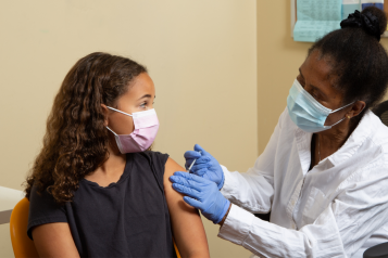 A female health worker vaccinating a young girl
